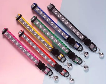 May include: Six colorful cat collars with paw print patterns and silver bells. The collars are in shades of pink, red, yellow, green, blue, and black. Each collar has a black buckle and a silver bell attached.