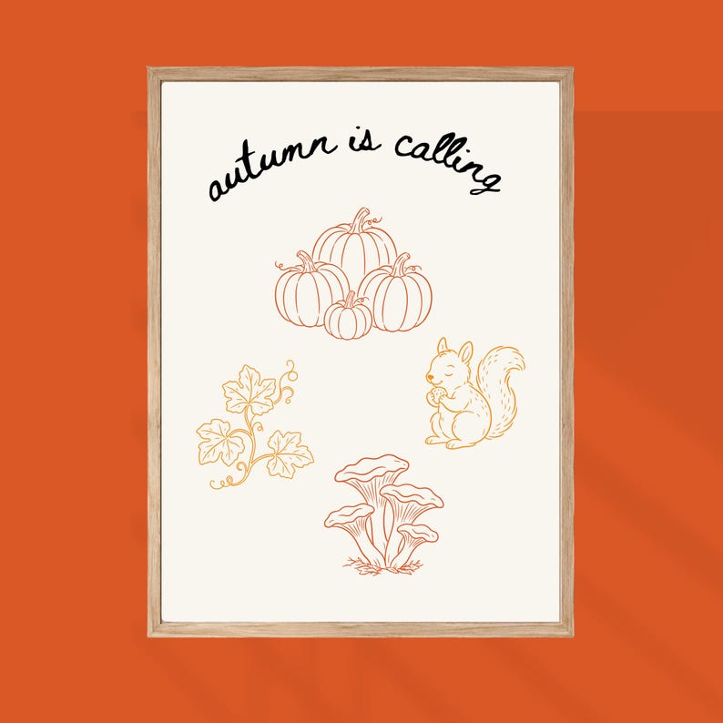 May include: A framed wall art print featuring the text "autumn is calling" in black script. The off-white background displays orange line art illustrations of a cluster of pumpkins, a squirrel holding an acorn, a leafy vine, and a group of mushrooms.