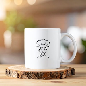 Puede incluir: Taza de cer&aacute;mica blanca con un dibujo lineal negro de un chef con gorro de cocinero y uniforme. La taza tiene un asa curva y est&aacute; sobre un posavasos de madera. El fondo est&aacute; borroso con luz natural.