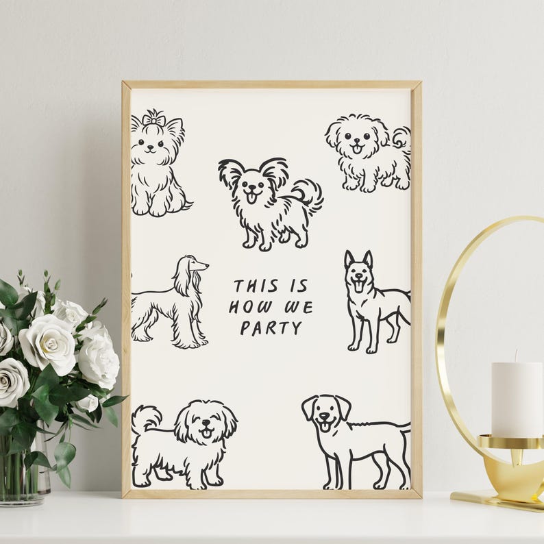 Op de afbeelding: Een ingelijste print met zwarte lijntekeningen van verschillende hondenrassen op een cr&egrave;mekleurige achtergrond. De tekst "THIS IS HOW WE PARTY" staat in het midden. De lijst is licht van kleur.