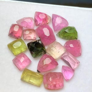 May include: A collection of faceted gemstones in various colors, including pink, green, yellow, and clear. The gemstones are arranged closely together, showcasing their different shapes and internal structures. The gems are likely tourmaline.