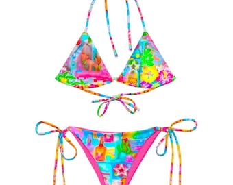 May include: A vibrant, colorful bikini set with a halter top and tie-side bottoms. The bikini features a psychedelic print with images of a woman, flowers, and cocktails. The edges are trimmed with pink fabric.