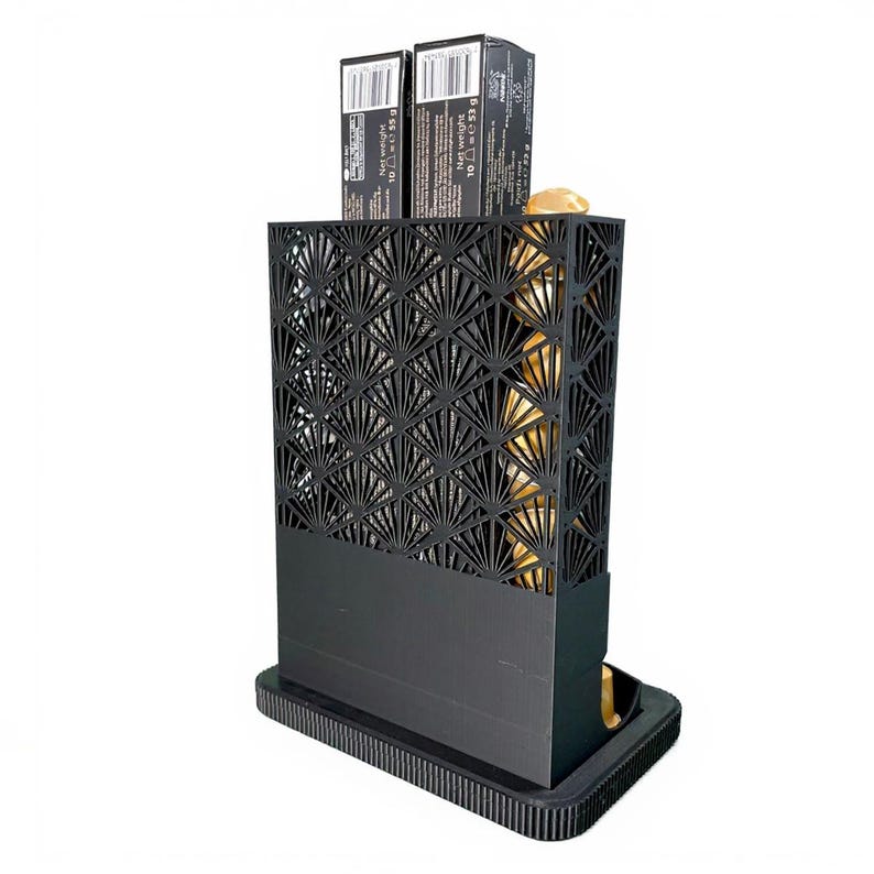 May include: A black, Art Deco-style decorative box with a geometric fan pattern. Two small black boxes sit on top. The interior appears to have a gold-colored lining. The base is rectangular with a ribbed edge.
