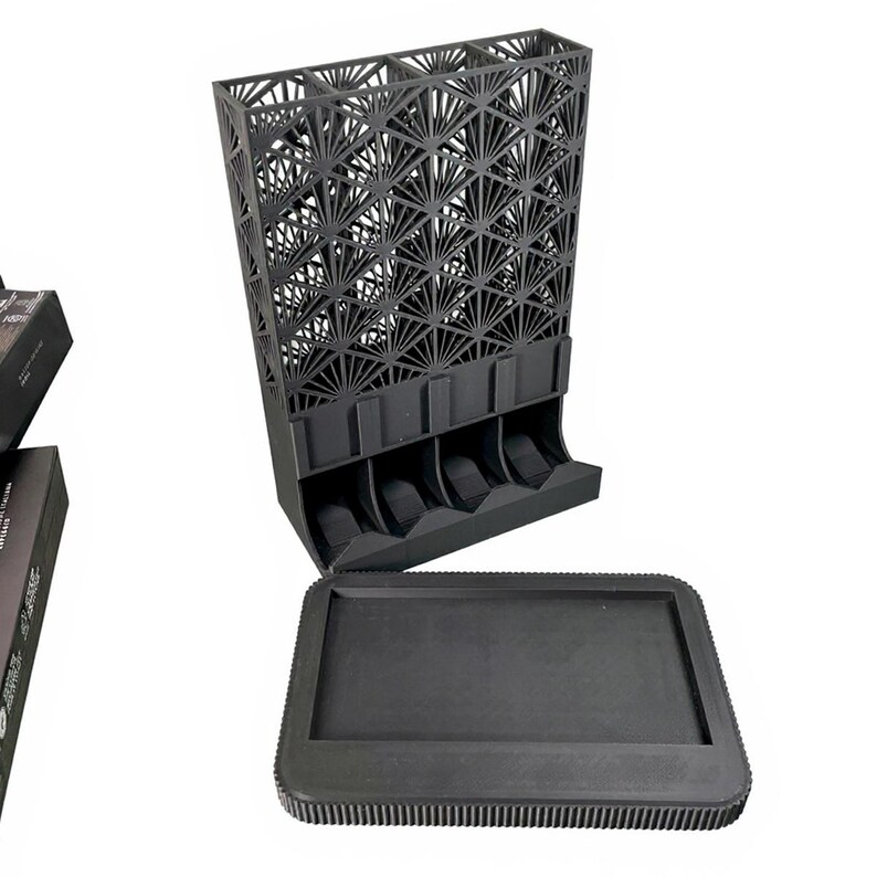 May include: A black, geometric, 3D-printed organizer with a decorative fan-like pattern. The organizer has multiple slots and a separate tray. The design is modern and functional, suitable for storing small items.