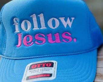 May include: Two trucker hats with the phrase "follow jesus." embroidered on the front. One hat is blue and the other is pink.