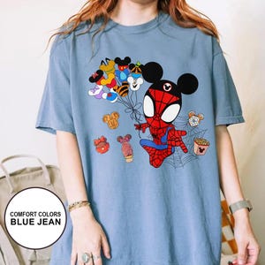 Puede incluir: Camiseta azul vaquero Comfort Colors con un personaje de dibujos animados de Spider-Man con orejas de Mickey Mouse. El dise&ntilde;o incluye globos tem&aacute;ticos de Mickey Mouse y varios alimentos. La camiseta tiene el texto "COMFORT COLORS BLUE JEAN".