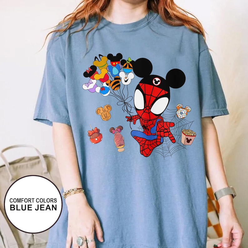 Puede incluir: Camiseta azul vaquero Comfort Colors con un personaje de dibujos animados de Spider-Man con orejas de Mickey Mouse. El dise&ntilde;o incluye globos tem&aacute;ticos de Mickey Mouse y varios alimentos. La camiseta tiene el texto "COMFORT COLORS BLUE JEAN".