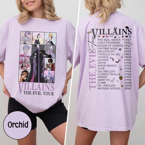 以下が含まれることがあります： ディズニーヴィランズのグラフィックが特徴の薄紫色のTシャツ。前面には「VILLAINS THE EVIL TOUR」の文字とキャラクターのコラージュが描かれています。背面にはヴィランズと年号が記載されています。シャツには「Orchid」と表示されています。