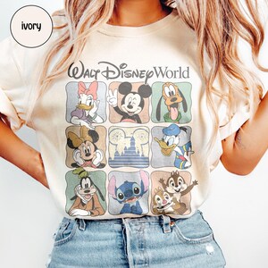 Pu&ograve; includere: T-shirt color avorio con una griglia di personaggi Disney, tra cui Topolino, Minnie, Paperino e Stitch. Le parole "Walt Disney World" sono stampate sopra la griglia in un carattere stilizzato. La maglietta ha un girocollo e maniche corte.
