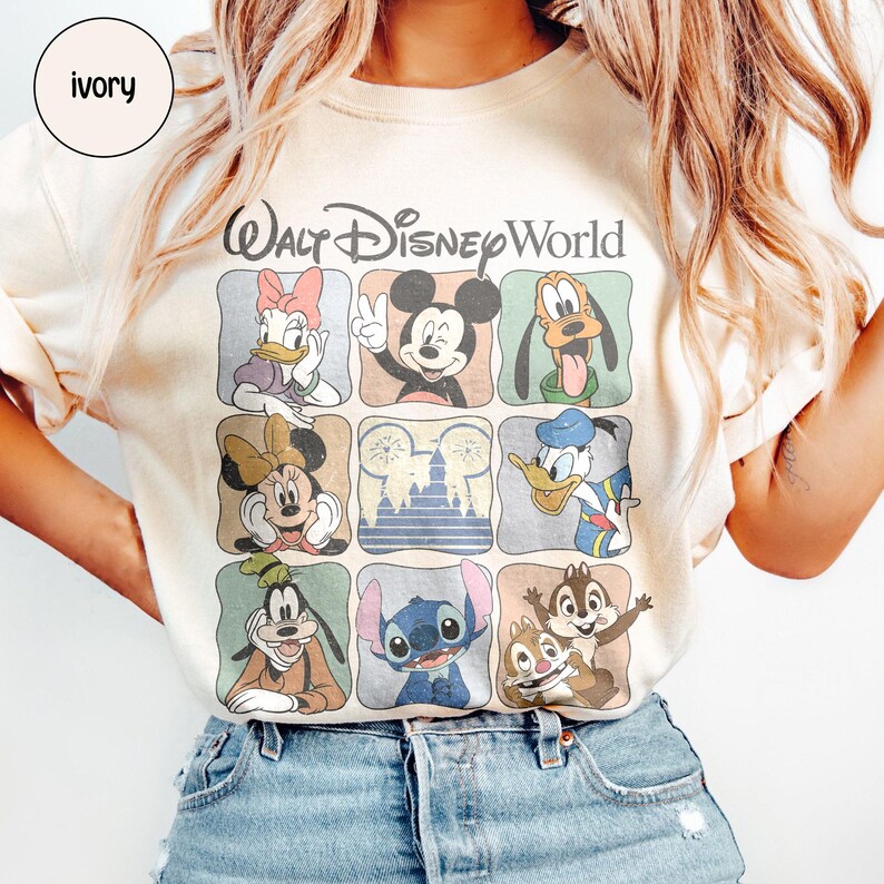 Pu&ograve; includere: T-shirt color avorio con una griglia di personaggi Disney, tra cui Topolino, Minnie, Paperino e Stitch. Le parole "Walt Disney World" sono stampate sopra la griglia in un carattere stilizzato. La maglietta ha un girocollo e maniche corte.