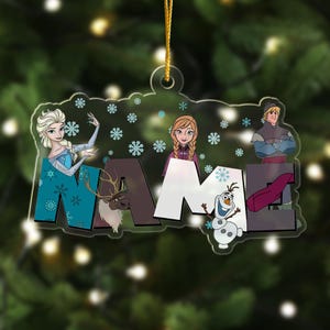May include: A clear acrylic Christmas ornament featuring the characters Elsa, Anna, Kristoff, Sven, and Olaf from Frozen. The word NAME is printed in large block letters across the center, surrounded by light blue snowflake icons and a gold string.