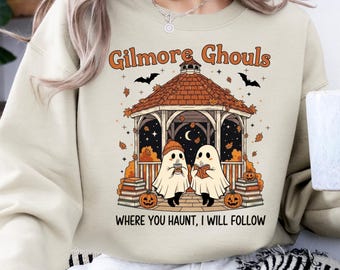 May include: Beige sweatshirt with a Halloween-themed graphic. The design features a gazebo with two ghost figures, pumpkins, bats, and the text "Gilmore Ghouls Where You Haunt, I Will Follow."
