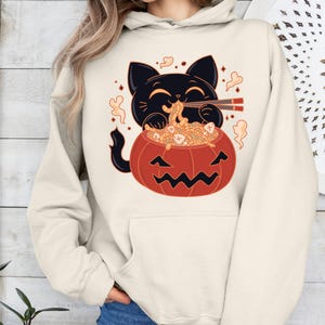 Black Cat Pumpkin Halloween Hoodie – Cute Cat in Pumpkin Eating Spaghetti– Funny Spooky Season Hoodie- Cute Spooky Season Hoodie