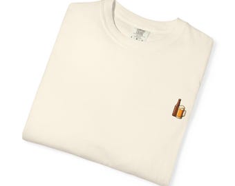 Könnte beinhalten: Cremefarbenes T-Shirt mit einem kleinen gestickten Design einer Bierflasche und einem Bierkrug. Das Shirt ist gefaltet und scheint aus einem weichen, bequemen Material zu sein. Das Etikett auf dem Shirt lautet "Comfort Colors".