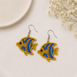 May include: A pair of dangle earrings featuring a fish-shaped design. The fish are embroidered with vibrant yellow and blue thread, showcasing a detailed mesh-like pattern and a small black bead for the eye. Each earring hangs from a silver-toned hook.