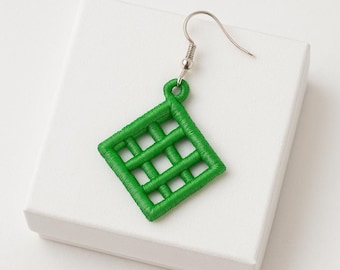 May include: A single green embroidered earring with a geometric grid design. The earring is a bright, vibrant green colour and features a silver-coloured fish hook. The earring is displayed on a white surface.