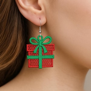 May include: Red and green embroidered gift box earrings. The earrings feature a red gift box design with a green bow and ribbon. The earrings are suspended from a silver-colored hook.