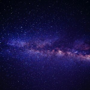 May include: A vibrant image of the night sky, showcasing a deep blue expanse dotted with countless stars. The Milky Way galaxy stretches across the frame, with hues of purple and pink, creating a stunning celestial display.