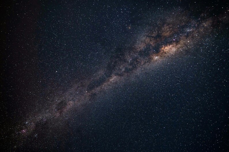 May include: A night sky filled with countless stars, showcasing the Milky Way galaxy. The image captures a dark blue expanse with a prominent, luminous band of stars and cosmic dust stretching across the frame.