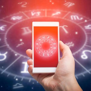 Peut inclure: Un smartphone blanc affiche un &eacute;cran rouge avec un graphique de roue du zodiaque. Le t&eacute;l&eacute;phone est tenu dans une main sur un fond de carte astrologique brillante avec des symboles du zodiaque. L'image a un th&egrave;me c&eacute;leste.