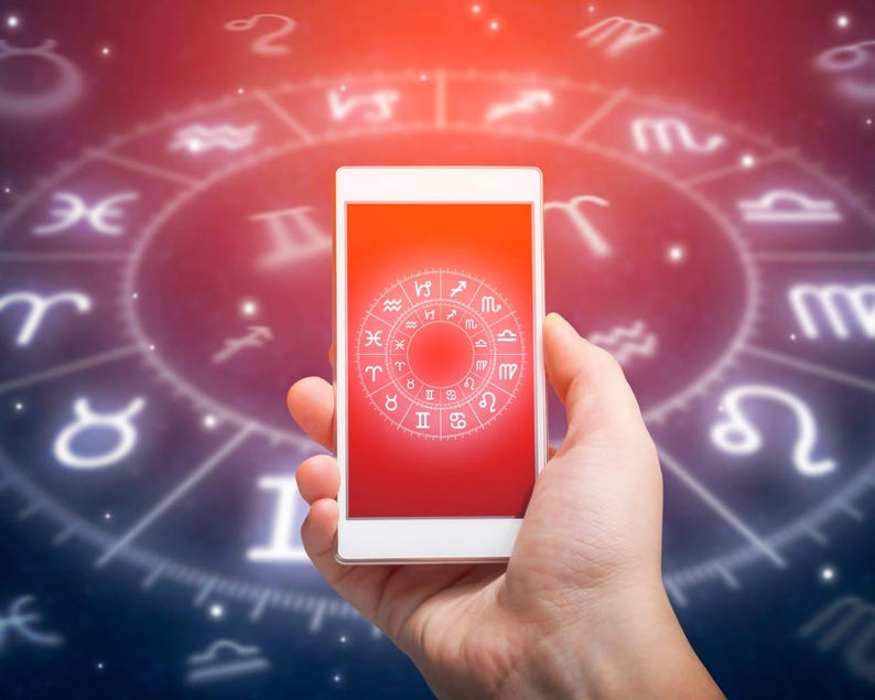 Peut inclure: Un smartphone blanc affiche un &eacute;cran rouge avec un graphique de roue du zodiaque. Le t&eacute;l&eacute;phone est tenu dans une main sur un fond de carte astrologique brillante avec des symboles du zodiaque. L'image a un th&egrave;me c&eacute;leste.