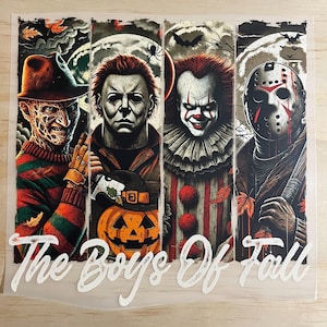 May include: A rectangular graphic print featuring four horror movie characters in vertical panels, including Freddy Krueger, Michael Myers, Pennywise, and Jason Voorhees, with the text The Boys Of Fall written in white script at the bottom.