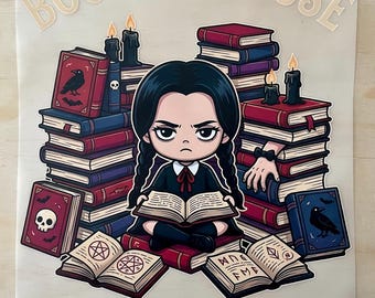 May include: A wooden sign featuring a cartoon illustration of a girl surrounded by stacks of books. The sign includes the text "BOOKS BECAUSE" at the top and "MURDER IS WRONG" at the bottom. The girl is reading a book, and there are lit candles.
