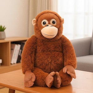 以下が含まれることがあります： フレンドリーな表情の茶色のぬいぐるみオランウータン。 ぬいぐるみは、大きくて丸い目、ベージュの顔、柔らかい茶色の毛皮をしています。 木製のテーブルの上に座っています。 このおもちゃは、抱きしめたくなるような、心安らぐアイテムです。