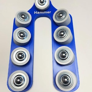 May include: A blue tool with the word "Hammer" printed on it. The tool has a U-shape with eight gray rollers with silver ball bearings. The rollers are evenly spaced along the blue frame.