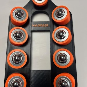 May include: Black holder with orange and silver roller bearings. The word "HAMMER" is printed on the holder. The roller bearings are arranged in a vertical pattern.