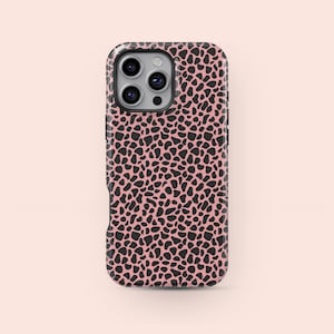 May include: A smartphone case featuring a pink base with a black, irregular spotted design. The case has a glossy finish and a camera aperture at the top.