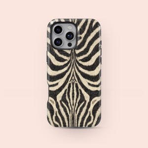 Könnte beinhalten: Eine Handyhülle mit Zebramuster. Die Hülle hat einen schwarzen Rand und ein Muster aus schwarzen und cremefarbenen Streifen, die die natürlichen Markierungen eines Zebras nachahmen. Die Hülle hat einen Kameraausschnitt.