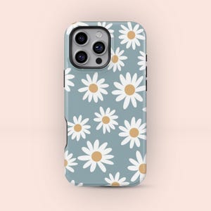 May include: A phone case with a daisy pattern. The case is light blue with white daisies and yellow centers. The phone case has a camera cutout and black side buttons.