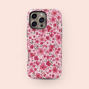 Puede incluir: Una funda de teléfono con un estampado floral rosa. La funda está cubierta con un patrón repetido de flores rosas y hojas verdes. Tiene un borde negro y una abertura para la cámara.