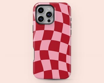 Puede incluir: Funda de teléfono a cuadros rojos y rosas. La funda tiene un acabado brillante y un borde elevado alrededor de la cámara. El diseño presenta un patrón de tablero de ajedrez ondulado en tonos rojos y rosas.