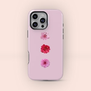May include: A pale pink phone case adorned with three floral designs in shades of pink and red. The case has a camera aperture and black side buttons. The flowers are a light pink, red, and a darker pink.
