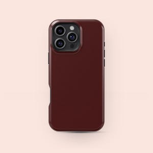 Op de afbeelding: Een bordeauxrode telefoonhoes met een getextureerde afwerking. De hoes heeft een vierkante vorm met afgeronde hoeken en een uitsparing voor de camera. De hoes is ontworpen om op een smartphone te passen en deze te beschermen tegen schade.