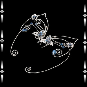 May include: Silver-toned elf ear cuffs with delicate floral and leaf accents. The design features small blue crystal beads and stylized flowers. The ear cuffs have a whimsical, fantasy-inspired aesthetic, perfect for cosplay or themed events.
