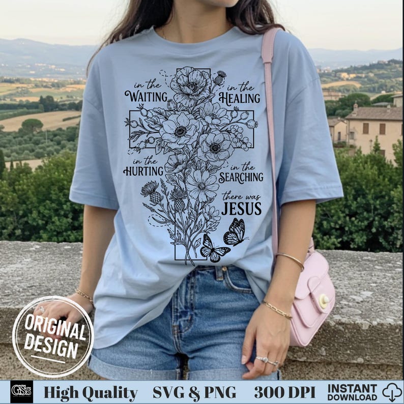 Woman in a light blue t-shirt modeling a black outline floral cross Jesus graphic design.