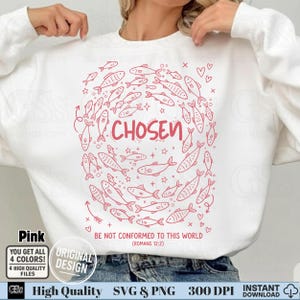 Model wearing a white sweatshirt with a pink line-art "Chosen" Romans 12:2 scripture design.