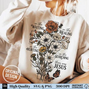 Close up of a woman in a cream sweatshirt featuring a retro floral cross Christian graphic.