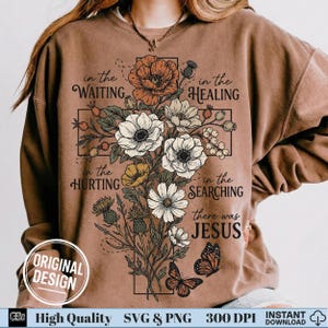 Woman wearing a brown sweatshirt with a vintage floral cross and the quote in the waiting there was Jesus.