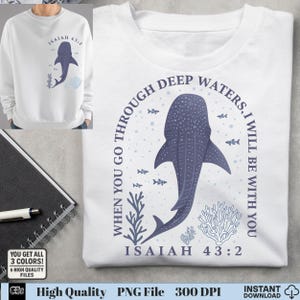 May include: White sweatshirt with a whale shark illustration and the text "WHEN YOU GO THROUGH DEEP WATERS, I WILL BE WITH YOU ISAIAH 43:2". The design incorporates blue fish and coral elements.
