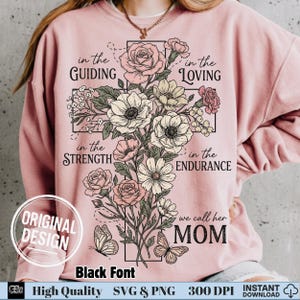 May include: Pink sweatshirt with a floral cross design. The cross is composed of roses, anemones, and other flowers. Text includes "in the Guiding, Loving, Strength, Endurance" and "we call her MOM". The design also features butterflies.
