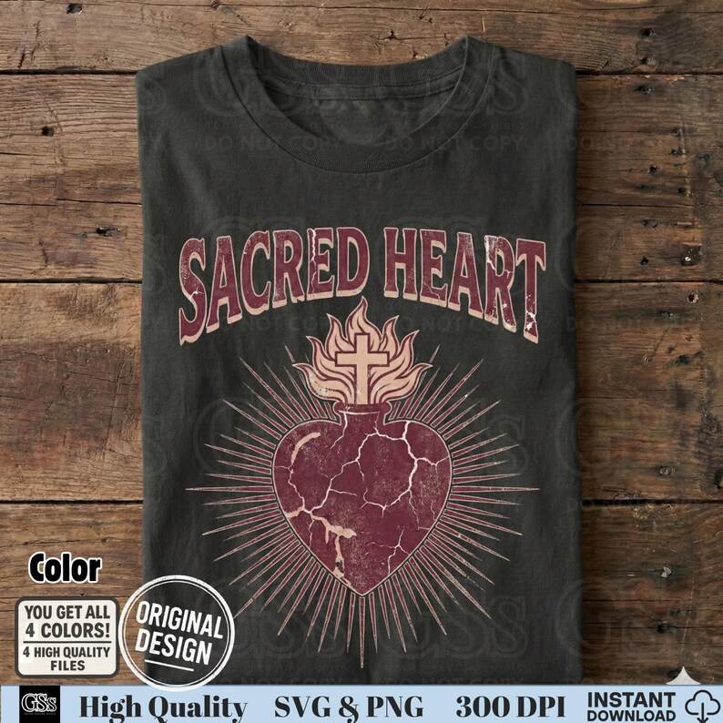 Op de afbeelding: Donkergrijs t-shirt met de tekst "SACRED HEART" boven een bordeauxrood hartontwerp met een kruis en vlammen. Het hart heeft een gebarsten textuur met stralende lijnen. Het shirt heeft een vintage uitstraling.