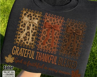 May include: Black sweatshirt with a fall design. It features three leopard print panels with bows, and the embroidered words "Grateful, Thankful, Blessed". The phrase "God is faithful in every season" is also embroidered on the sweatshirt.