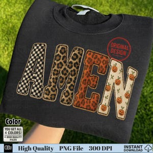 May include: Black sweatshirt with the word "AMEN" in a unique design. The letter "A" has a black and white checkered pattern, "M" has a leopard print, "E" has an orange leopard print, and "N" has a pumpkin pattern. The words "Original Design" are in a red circle.