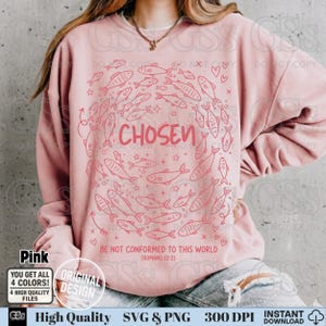 May include: Pink sweatshirt with a fish design in a circle around the word "CHOSEN". The text "BE NOT CONFORMED TO THIS WORLD (ROMANS 12:2)" is below the design. The sweatshirt has a crew neck and long sleeves.