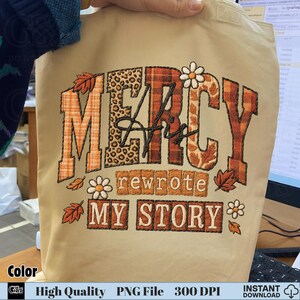 Beige tote bag mockup with “Mercy His Rewrote My Story” sublimation clipart