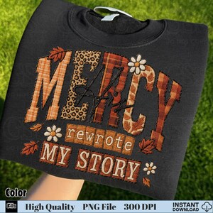 Folded sweatshirt with “Mercy His Rewrote My Story” fall embroidery PNG design